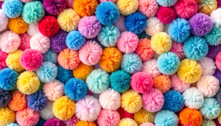 A vibrant collection of colorful pom-poms arranged closely together in a dense pattern viewed from directly above